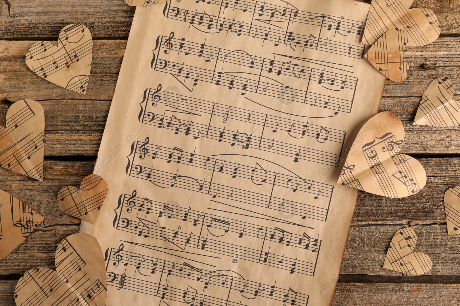 Photo of Paper hearts with notes and musical note sheet on wooden table, flat lay