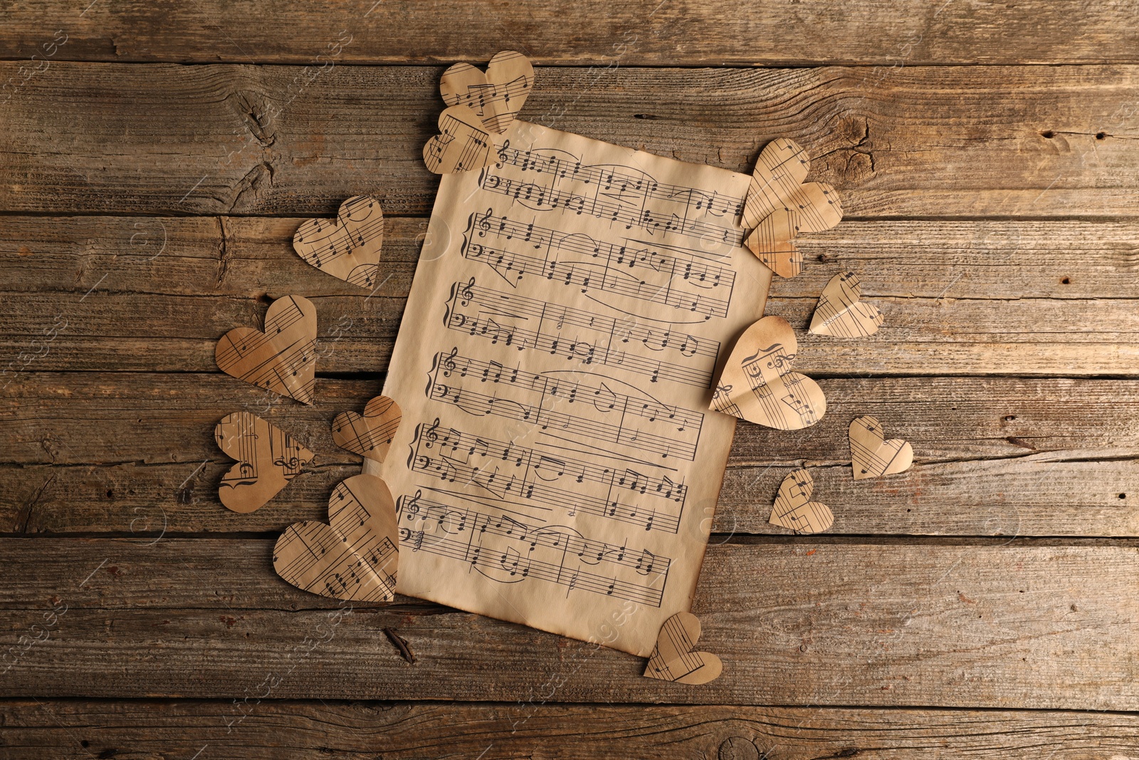 Photo of Paper hearts with notes and musical note sheet on wooden table, flat lay