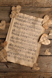 Photo of Paper hearts with notes and musical note sheet on wooden table, flat lay