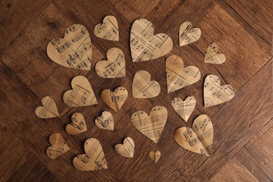 Photo of Paper hearts with notes on wooden table, flat lay