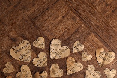 Photo of Paper hearts with notes on wooden table, flat lay. Space for text