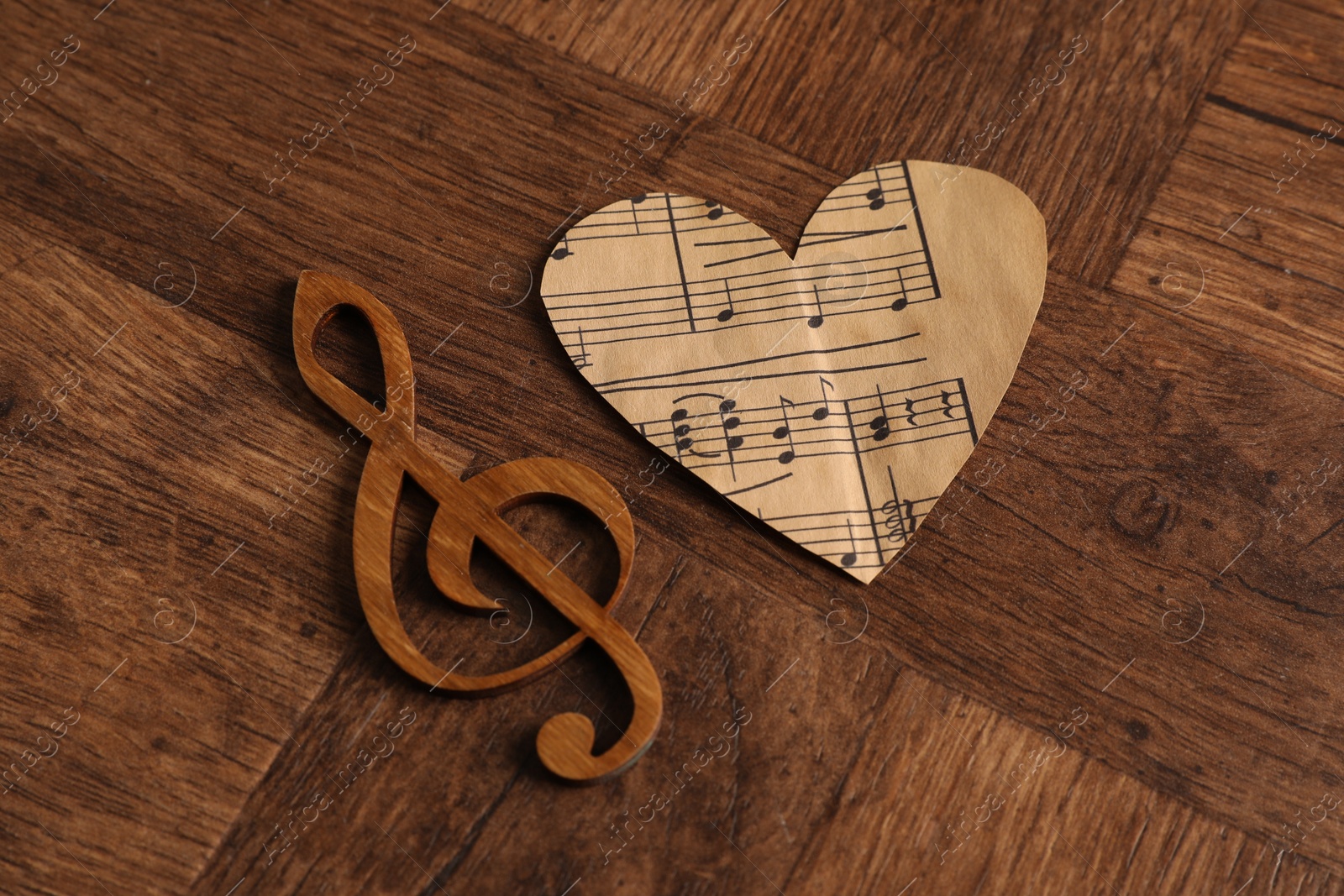 Photo of Paper heart and clef note on wooden table, above view