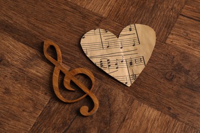 Paper heart and clef note on wooden table, above view