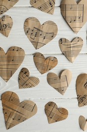 Paper hearts with notes on white wooden table, flat lay