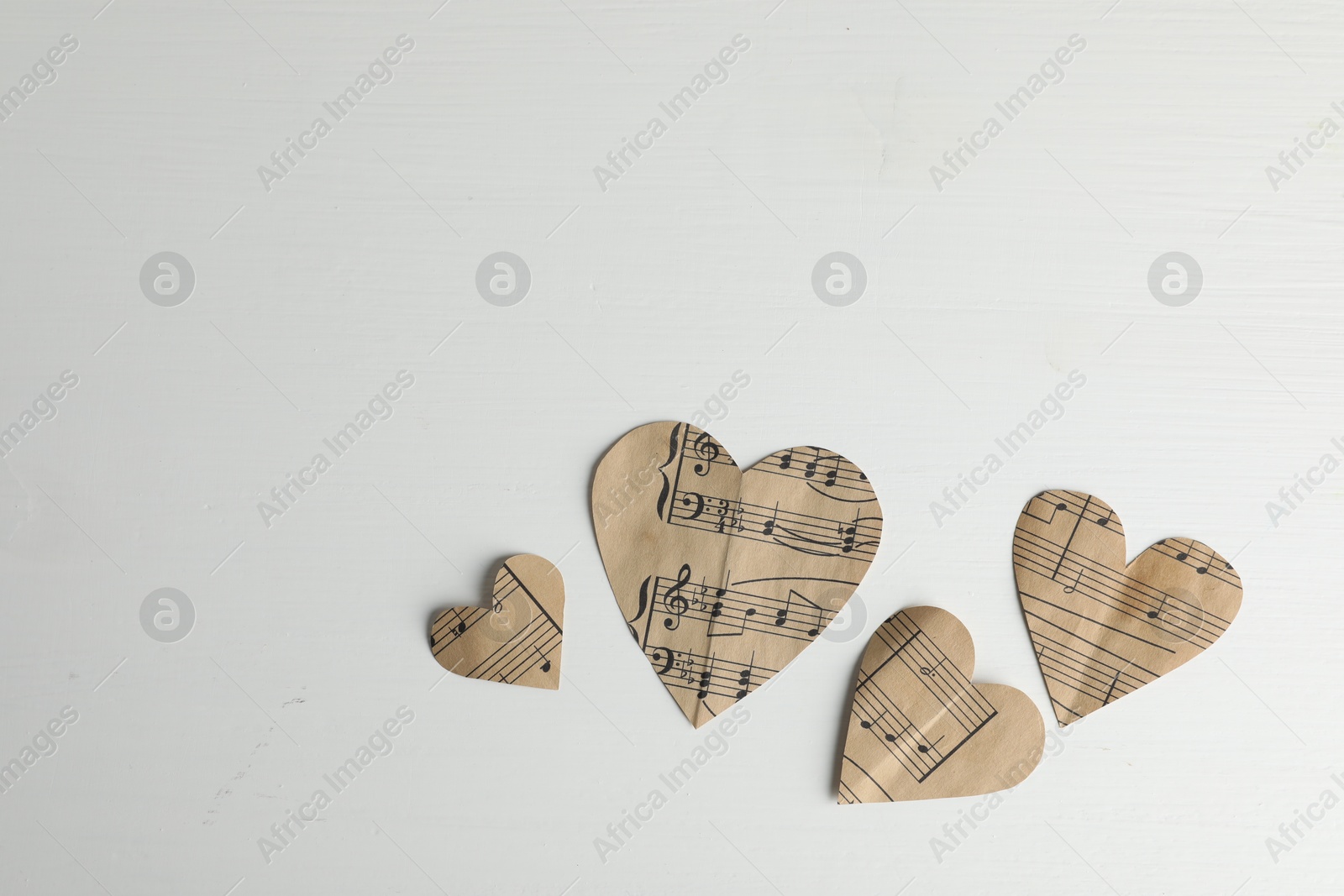 Photo of Paper hearts with notes on white wooden table, flat lay. Space for text