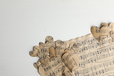 Photo of Paper hearts with notes and musical note sheet on white wooden table, flat lay. Space for text