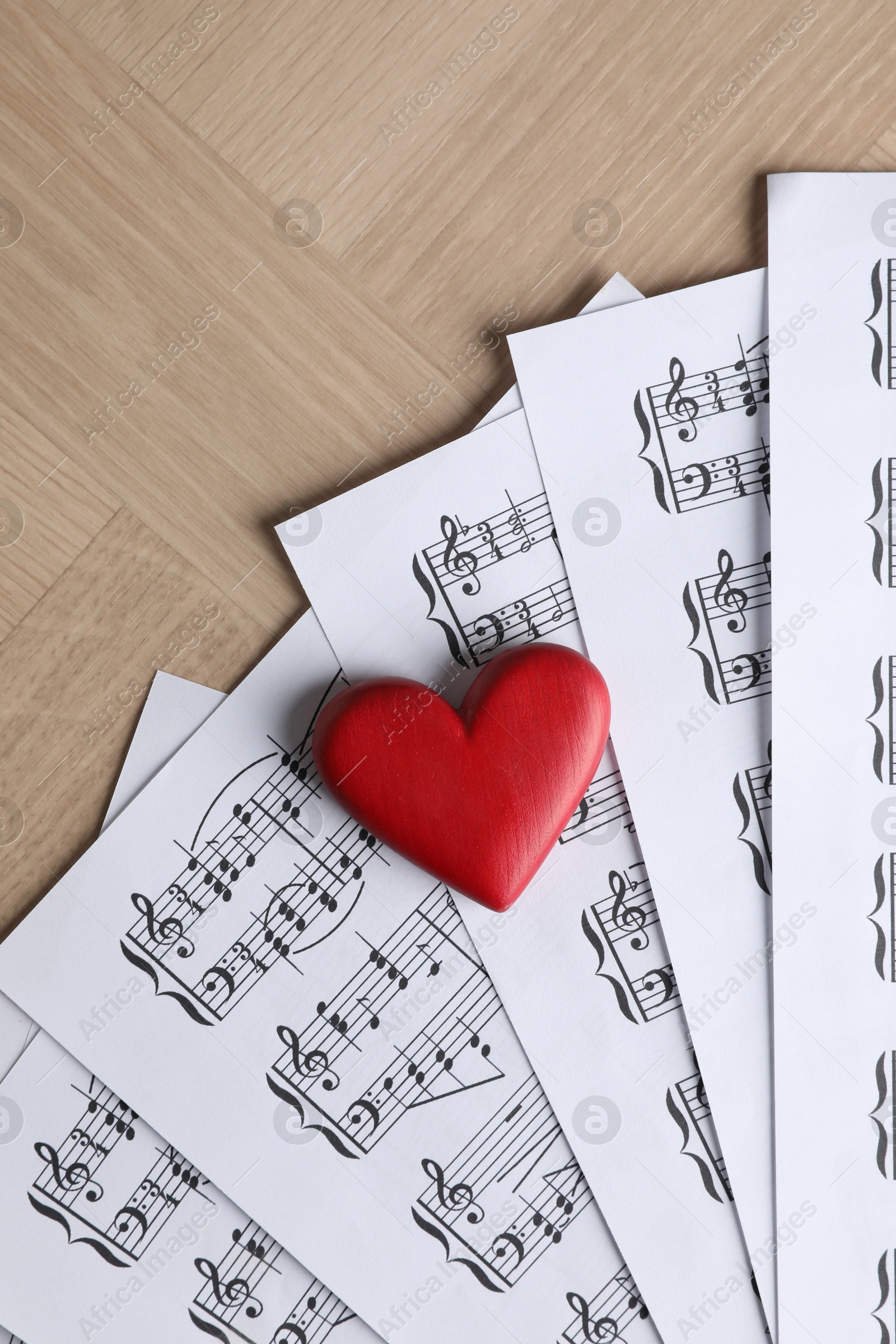 Photo of Heart figure and musical note sheets on wooden table, top view