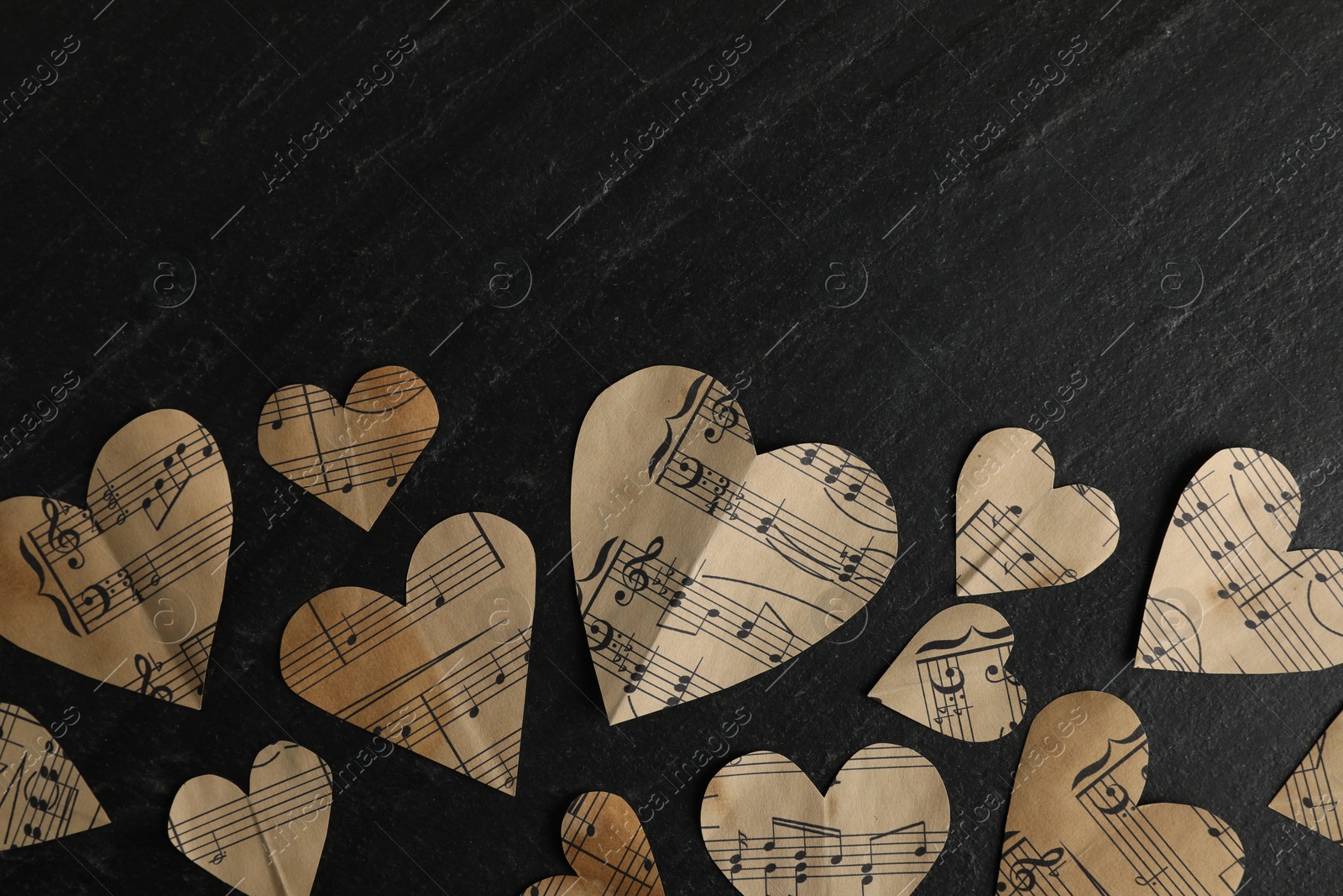 Photo of Paper hearts with notes on black table, flat lay. Space for text