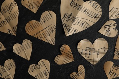 Photo of Paper hearts with notes on black table, flat lay