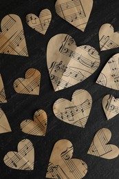 Photo of Paper hearts with notes on black table, flat lay