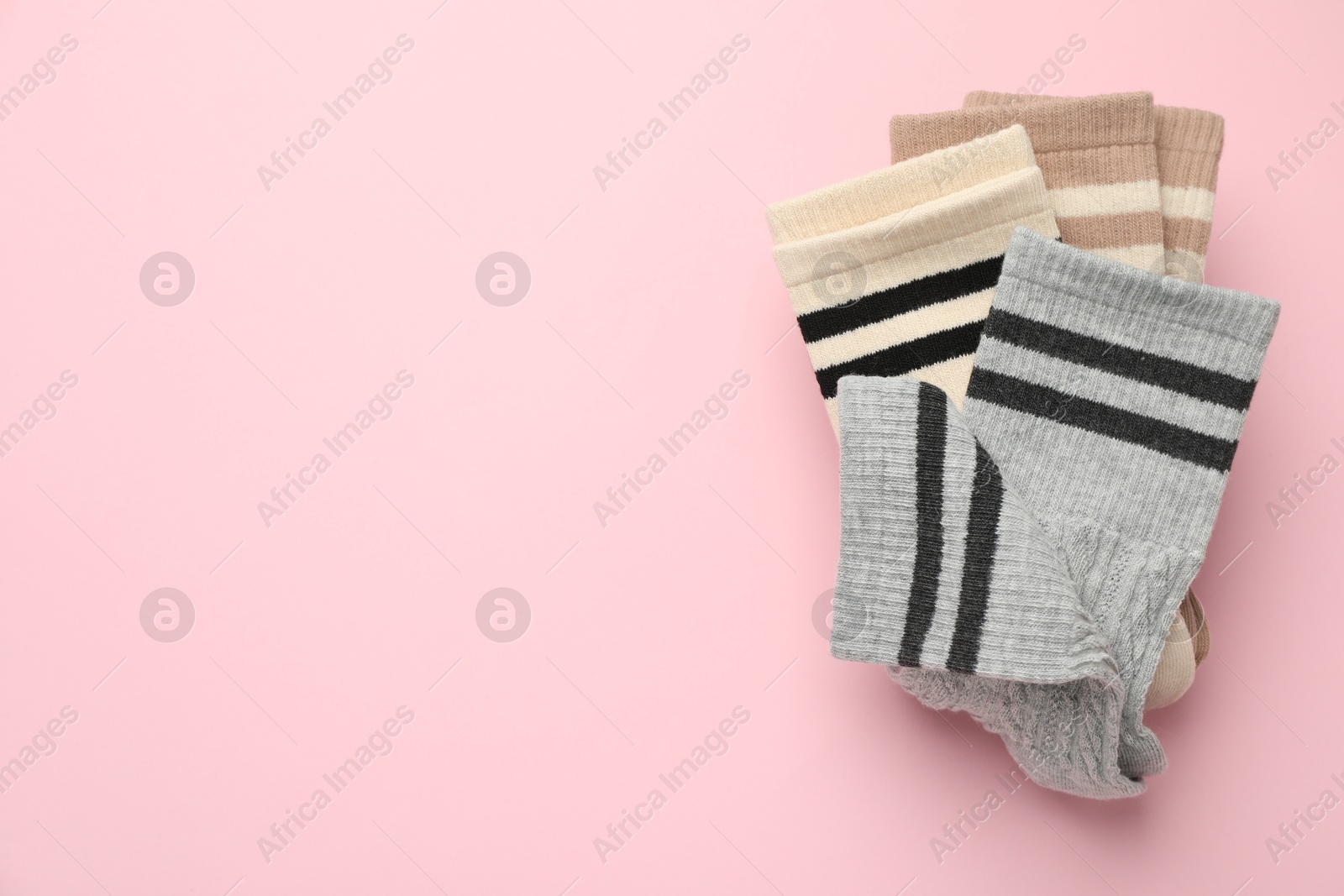 Photo of Different comfortable socks on light pink background, top view. Space for text