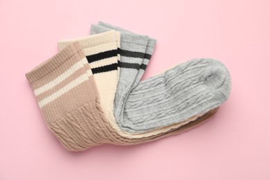 Photo of Different comfortable socks on light pink background, top view