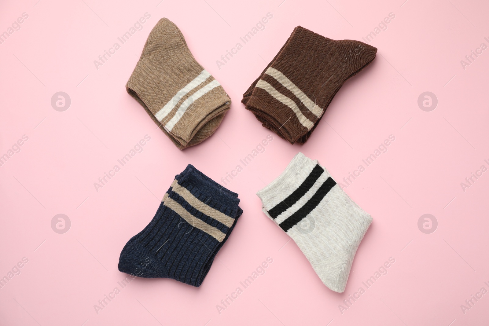 Photo of Different comfortable socks on light pink background, flat lay