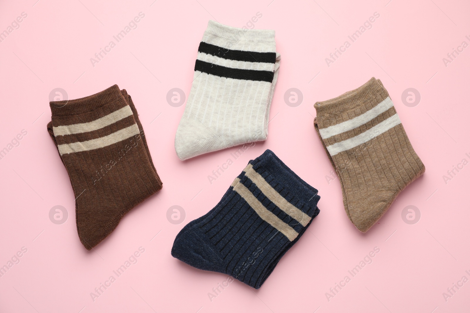 Photo of Different comfortable socks on light pink background, flat lay