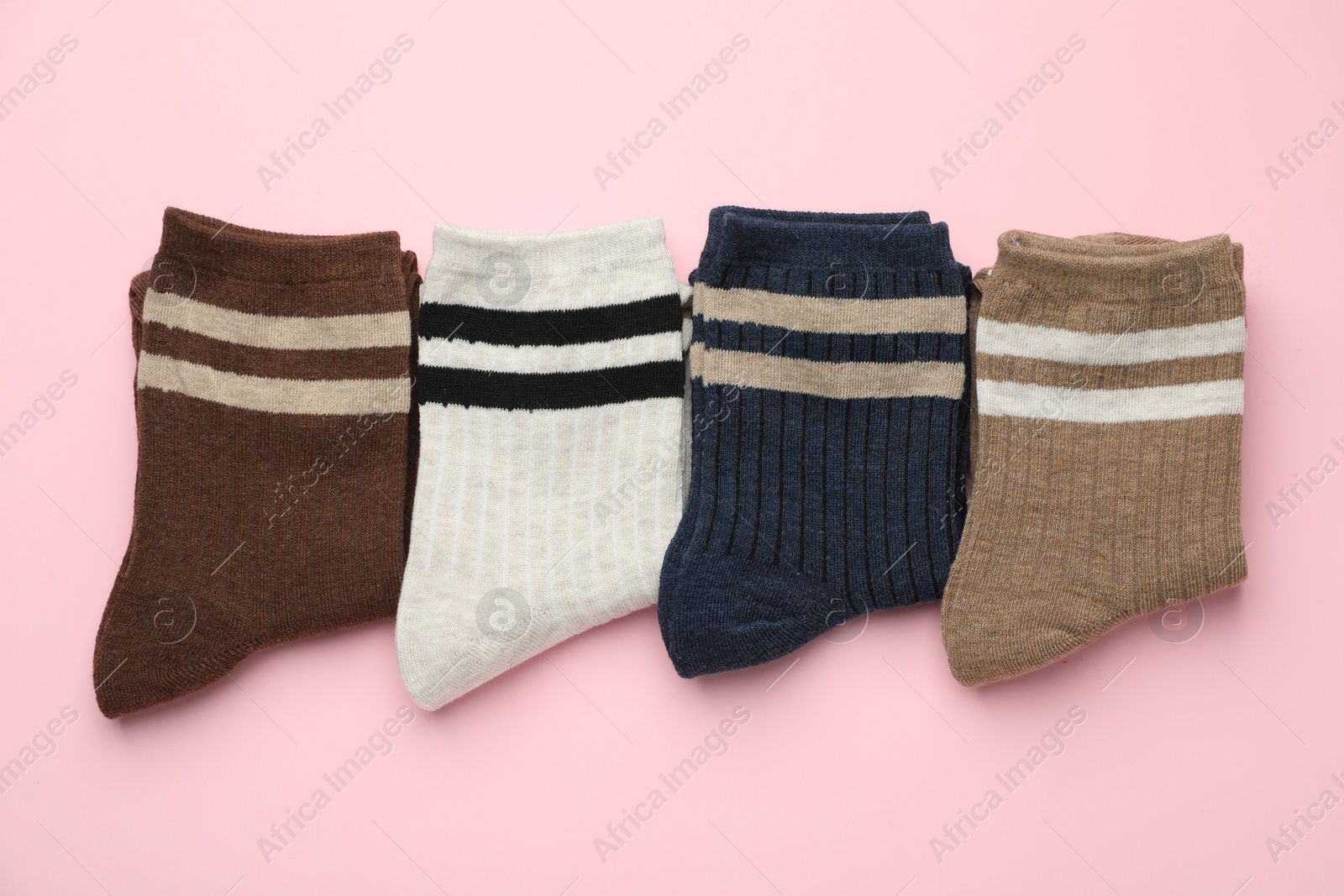 Photo of Different comfortable socks on light pink background, flat lay