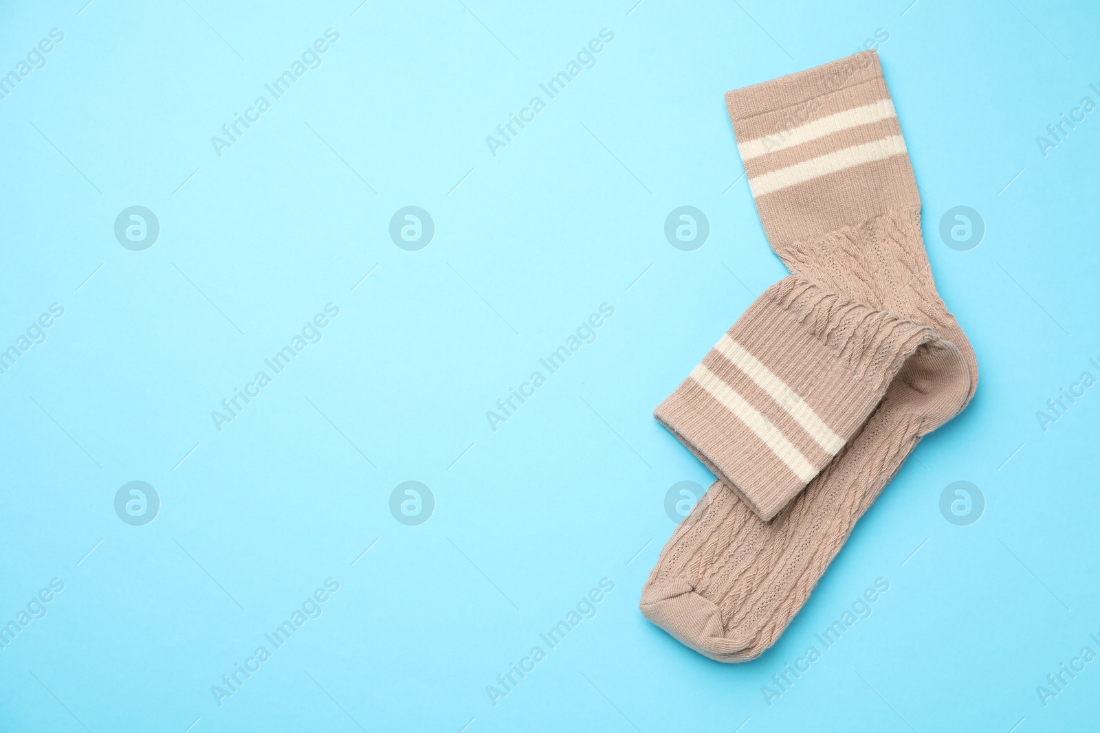 Photo of Pair of soft comfortable socks on light blue background, top view. Space for text