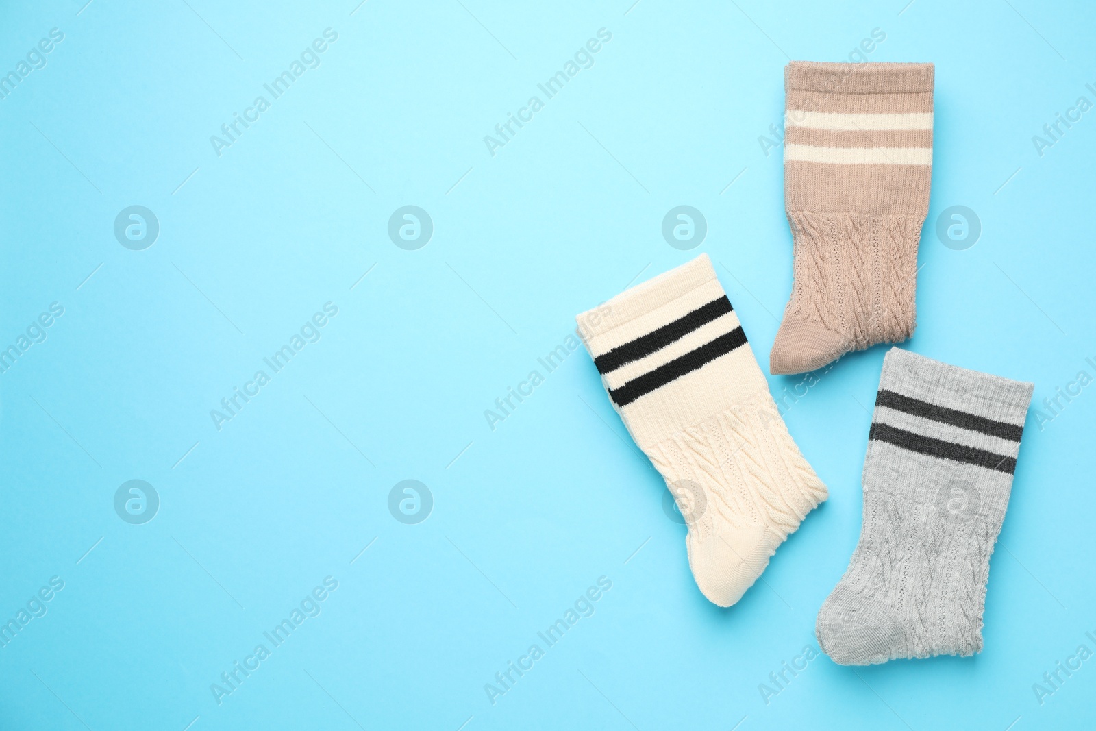 Photo of Different comfortable socks on light blue background, flat lay. Space for text