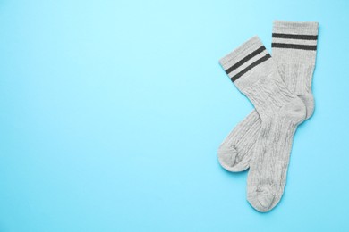 Photo of Pair of soft comfortable socks on light blue background, top view. Space for text