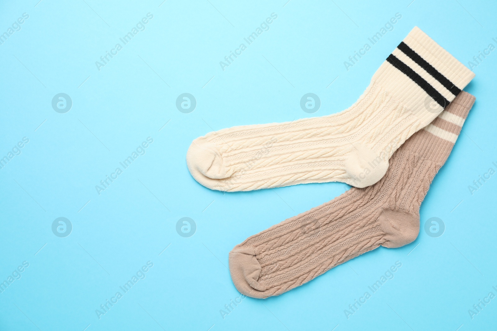 Photo of Different comfortable socks on light blue background, flat lay. Space for text