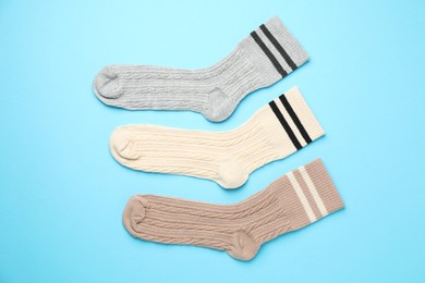 Photo of Different comfortable socks on light blue background, flat lay