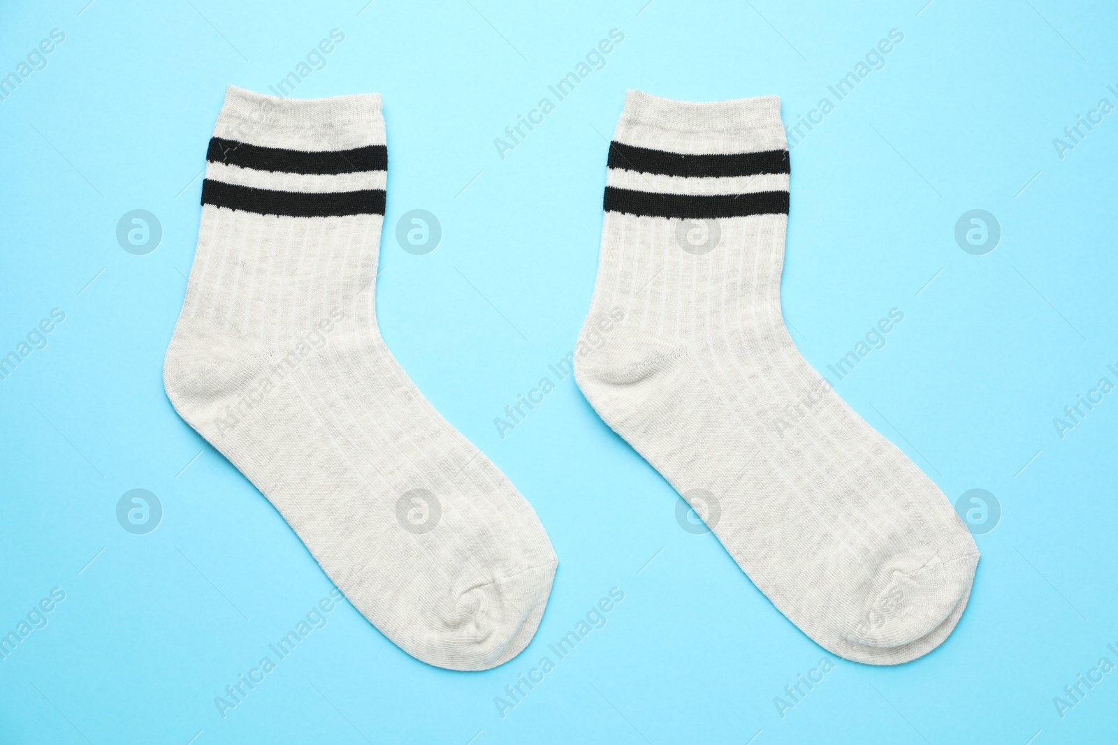 Photo of Pair of soft comfortable socks on light blue background, top view