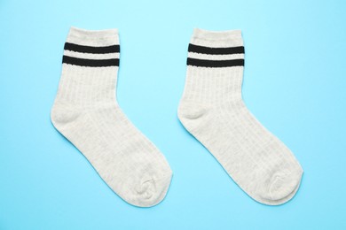 Photo of Pair of soft comfortable socks on light blue background, top view