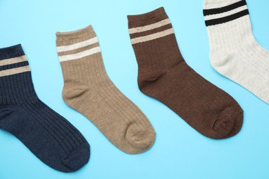 Photo of Different comfortable socks on light blue background, flat lay