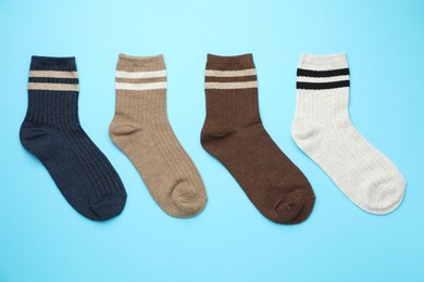 Photo of Different comfortable socks on light blue background, flat lay