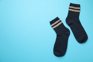 Photo of Pair of soft comfortable socks on light blue background, top view. Space for text