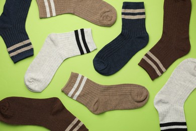 Photo of Different comfortable socks on light green background, flat lay