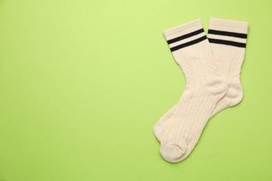 Photo of Pair of soft comfortable socks on light green background, top view. Space for text