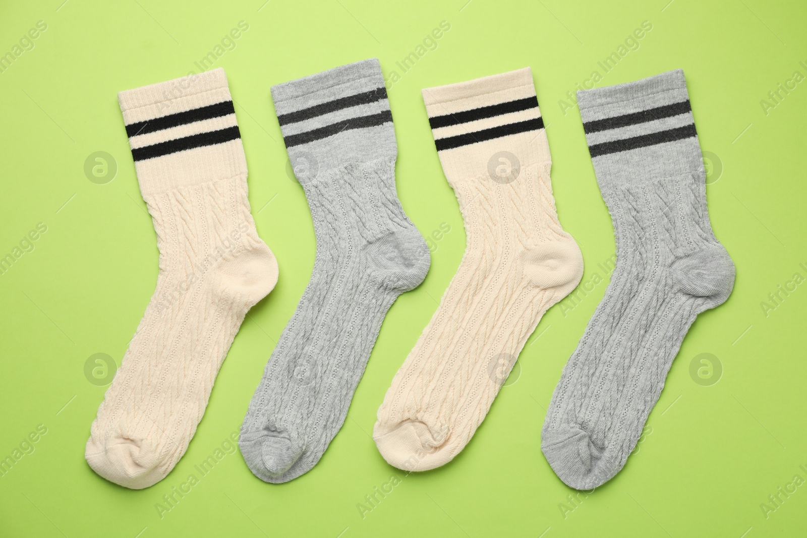 Photo of Different comfortable socks on light green background, flat lay