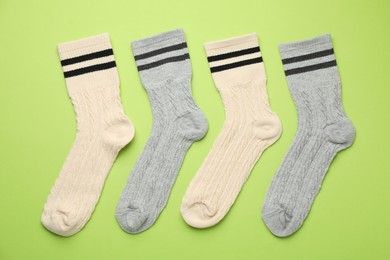 Photo of Different comfortable socks on light green background, flat lay