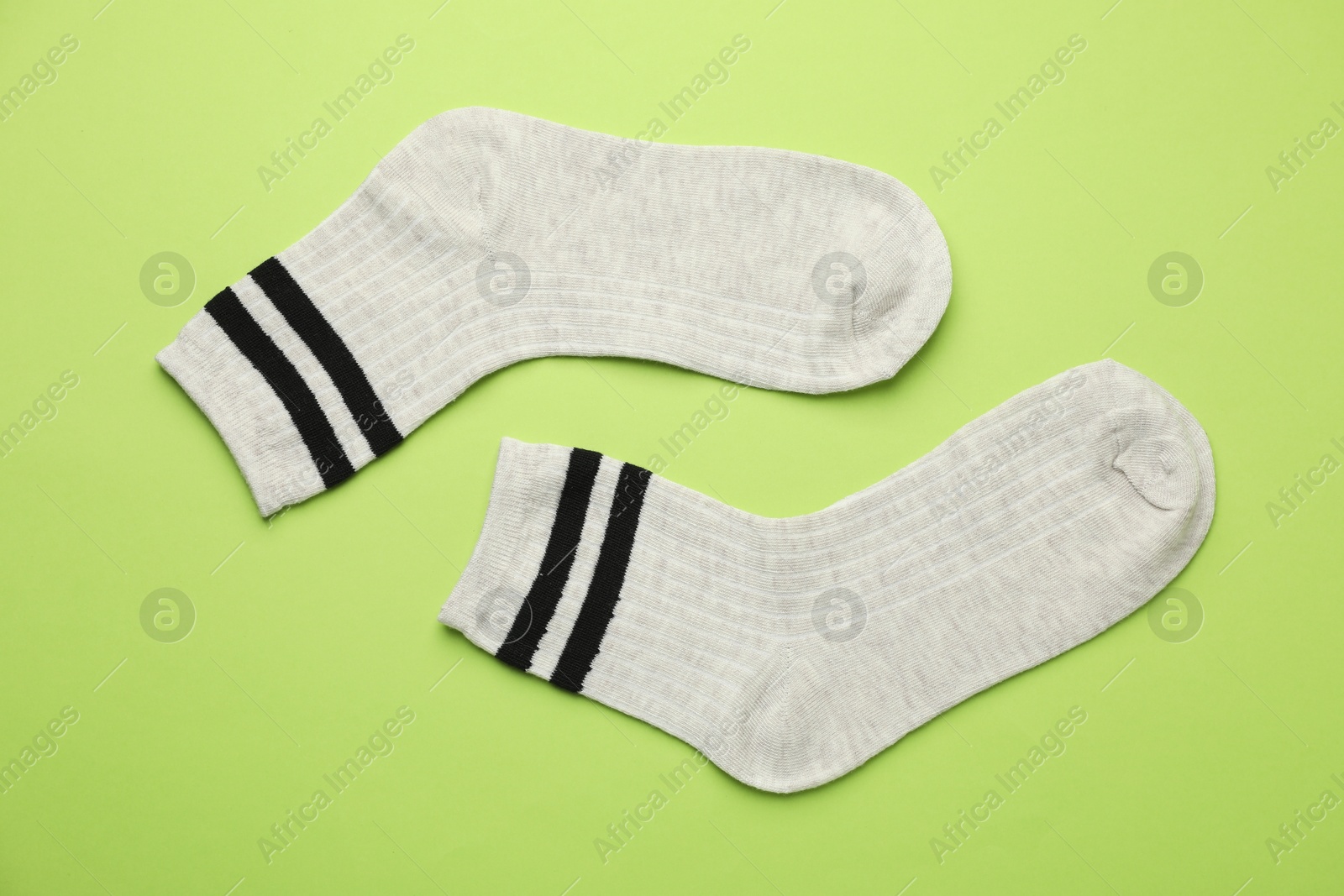 Photo of Pair of soft comfortable socks on light green background, top view