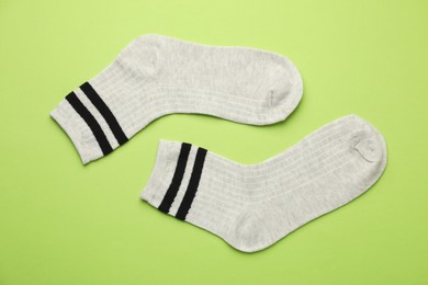 Photo of Pair of soft comfortable socks on light green background, top view