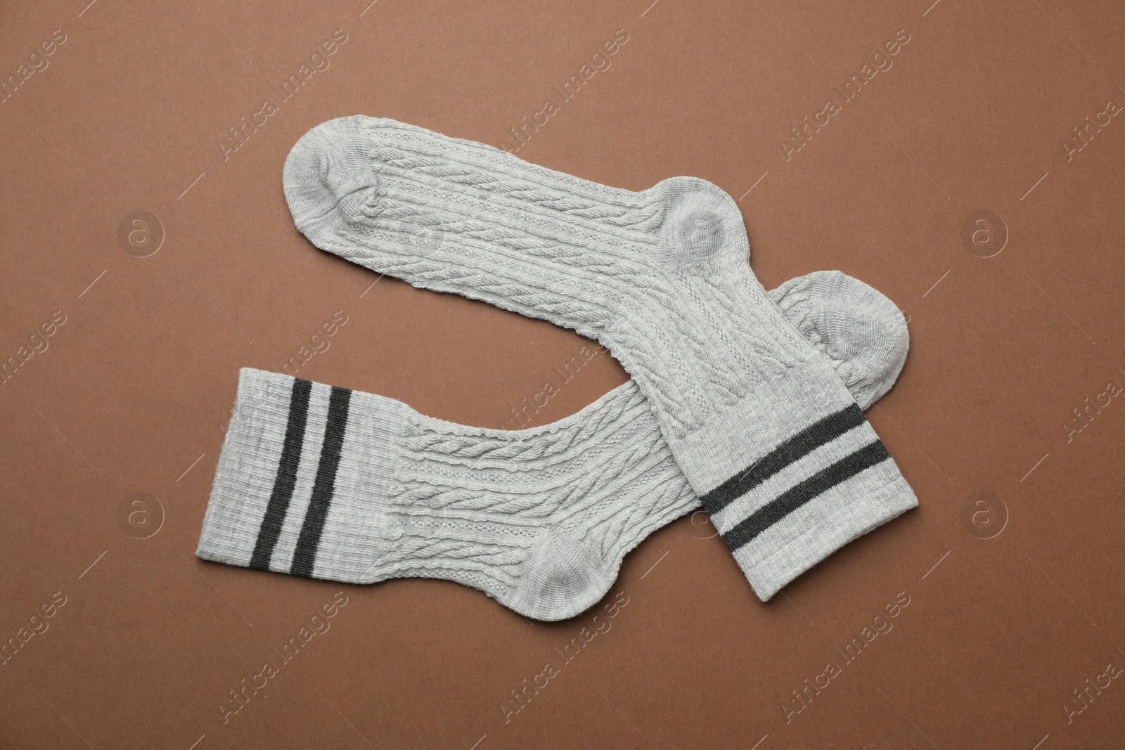 Photo of Pair of soft comfortable socks on brown background, top view