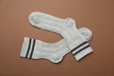 Photo of Pair of soft comfortable socks on brown background, top view