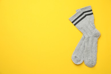 Photo of Pair of soft comfortable socks on yellow background, top view. Space for text