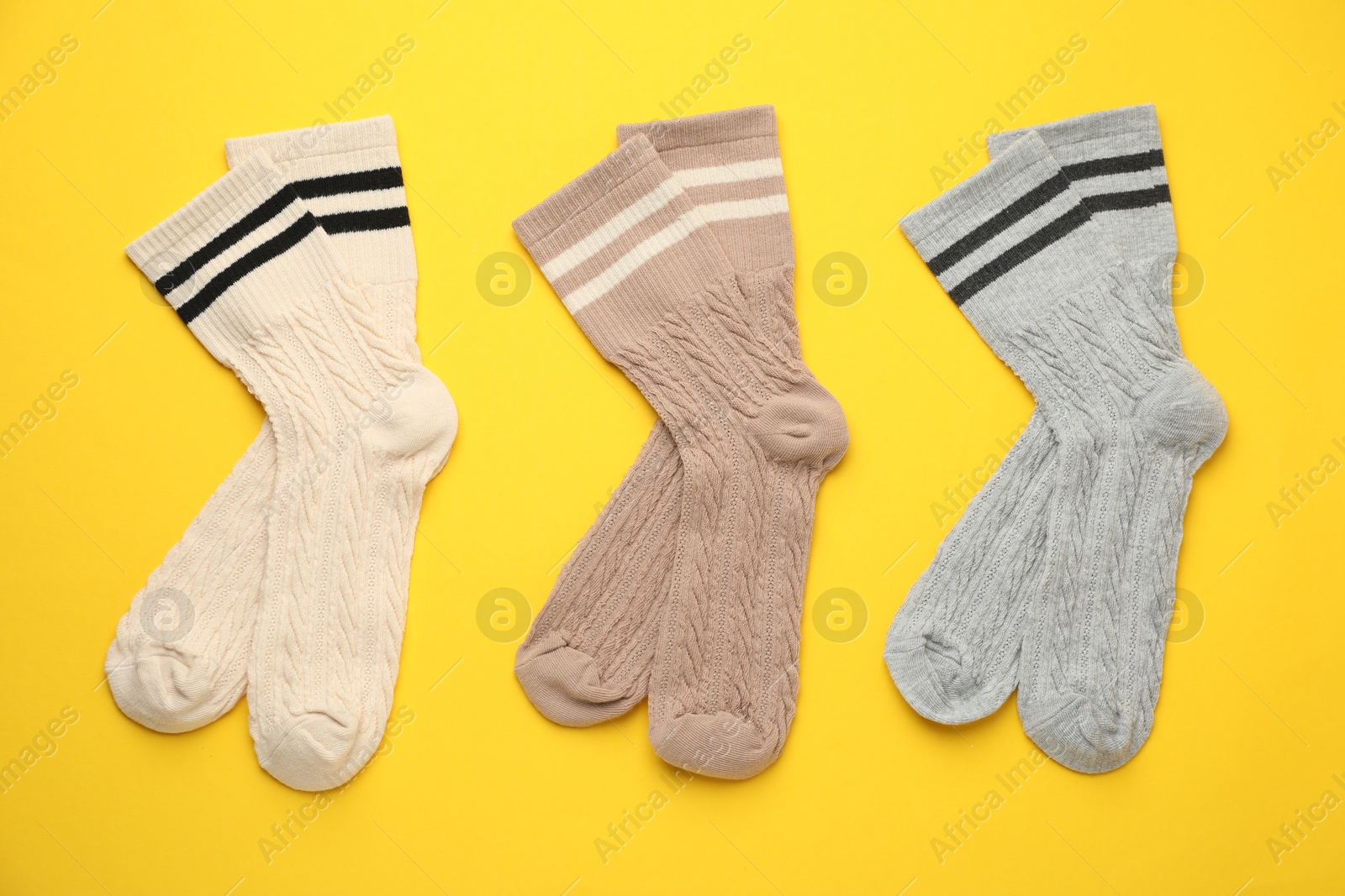 Photo of Different comfortable socks on yellow background, flat lay