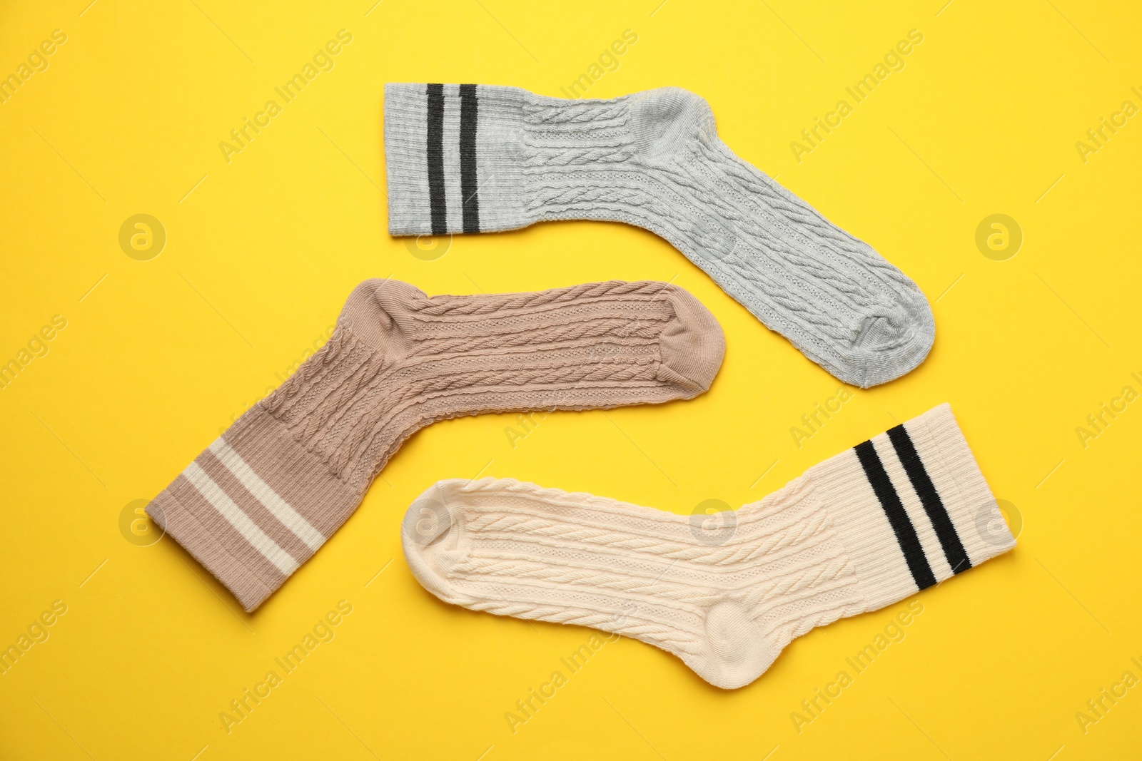 Photo of Different comfortable socks on yellow background, flat lay