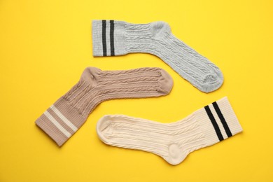 Photo of Different comfortable socks on yellow background, flat lay