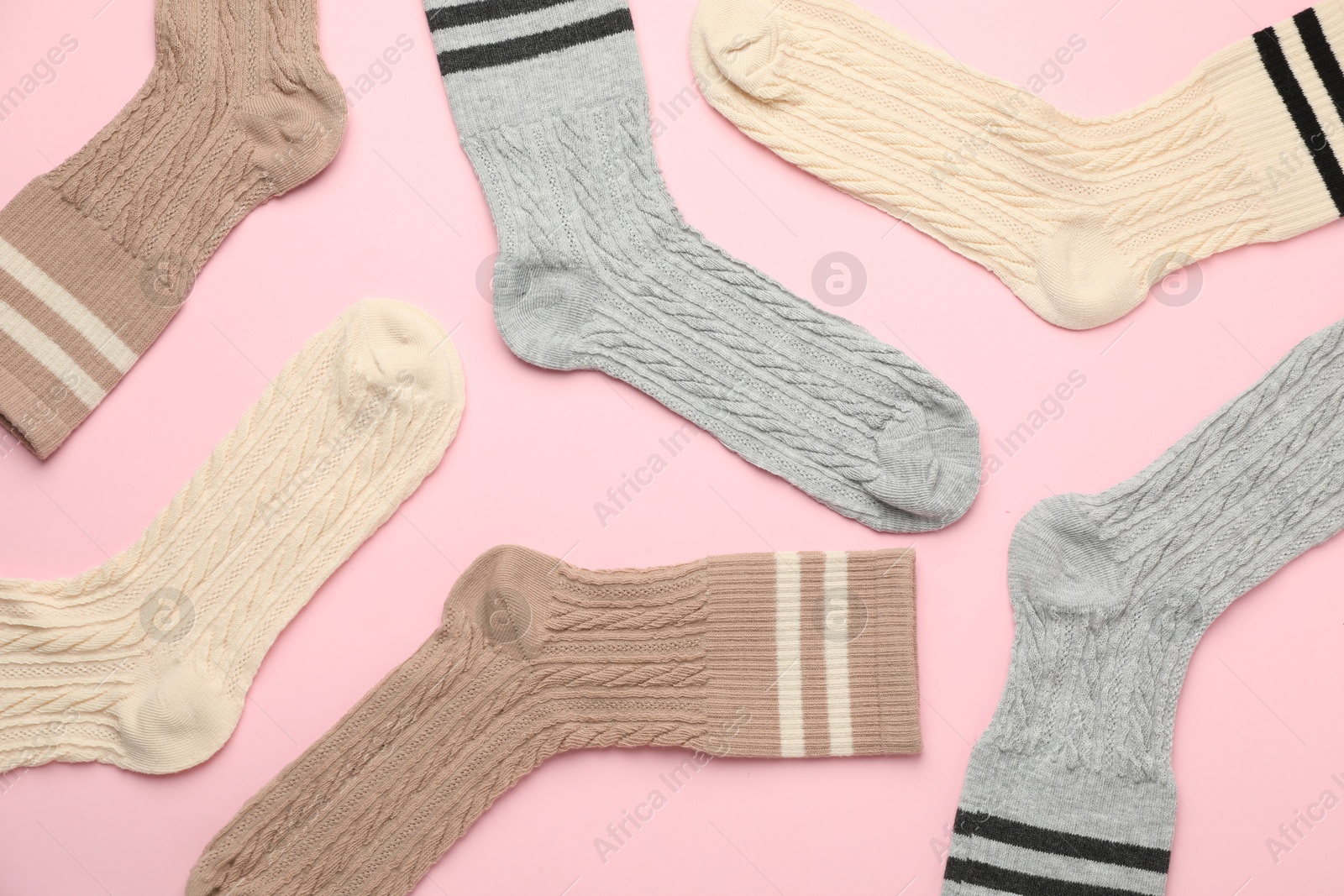 Photo of Different comfortable socks on light pink background, flat lay