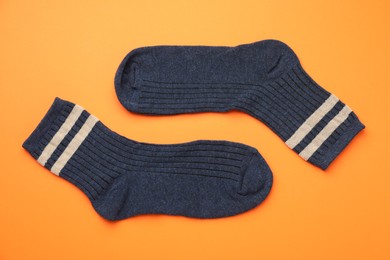 Photo of Pair of soft comfortable socks on orange background, top view