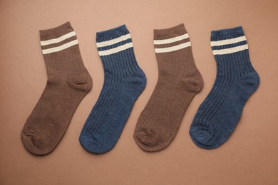 Photo of Different comfortable socks on brown background, flat lay