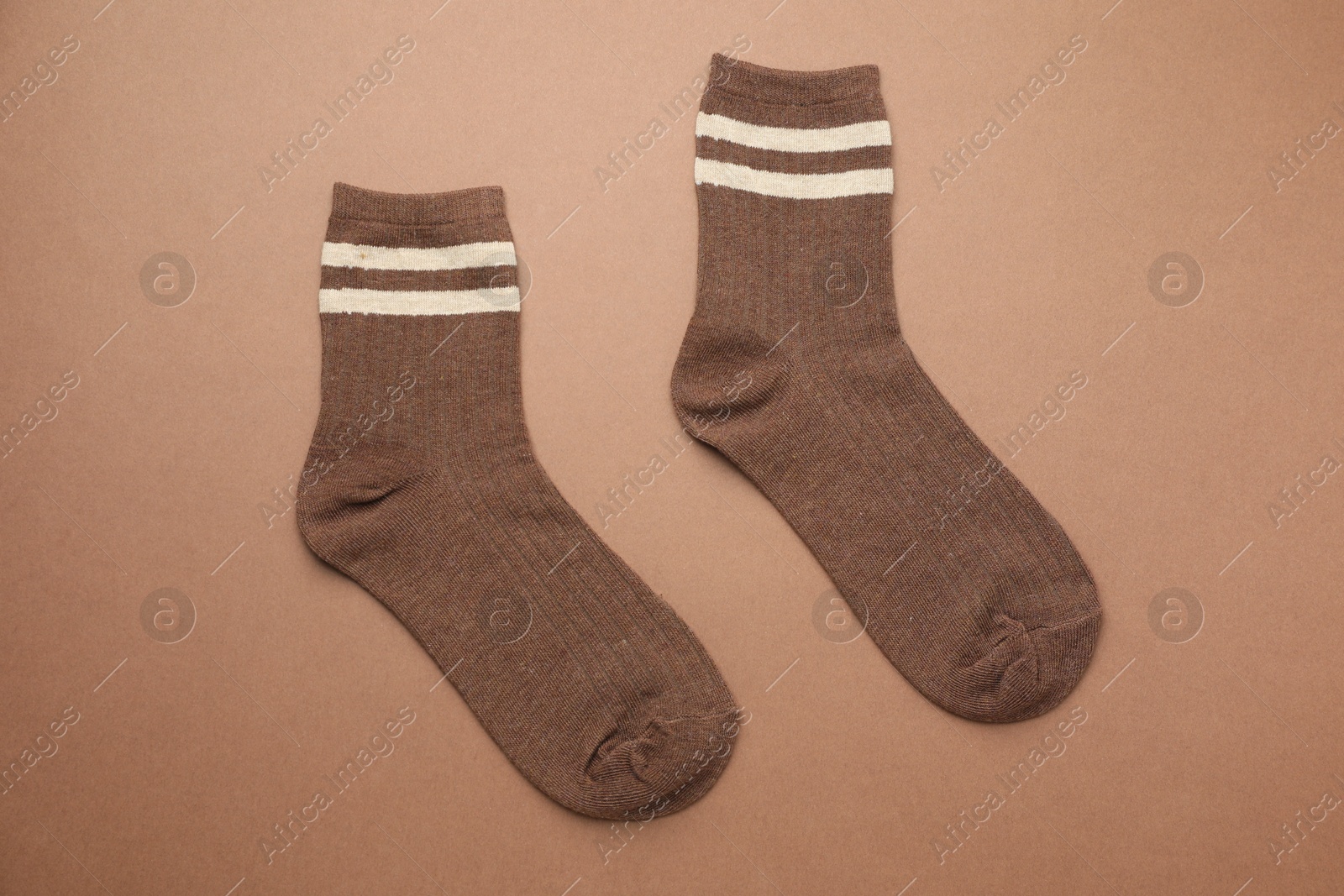 Photo of Pair of soft comfortable socks on brown background, top view