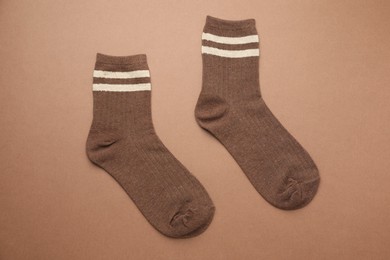 Photo of Pair of soft comfortable socks on brown background, top view