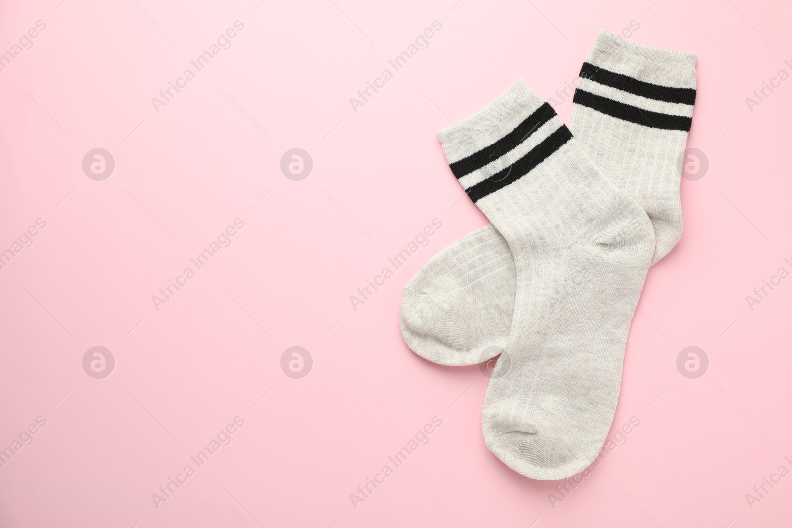 Photo of Pair of soft comfortable socks on light pink background, top view. Space for text