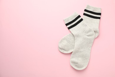 Photo of Pair of soft comfortable socks on light pink background, top view. Space for text