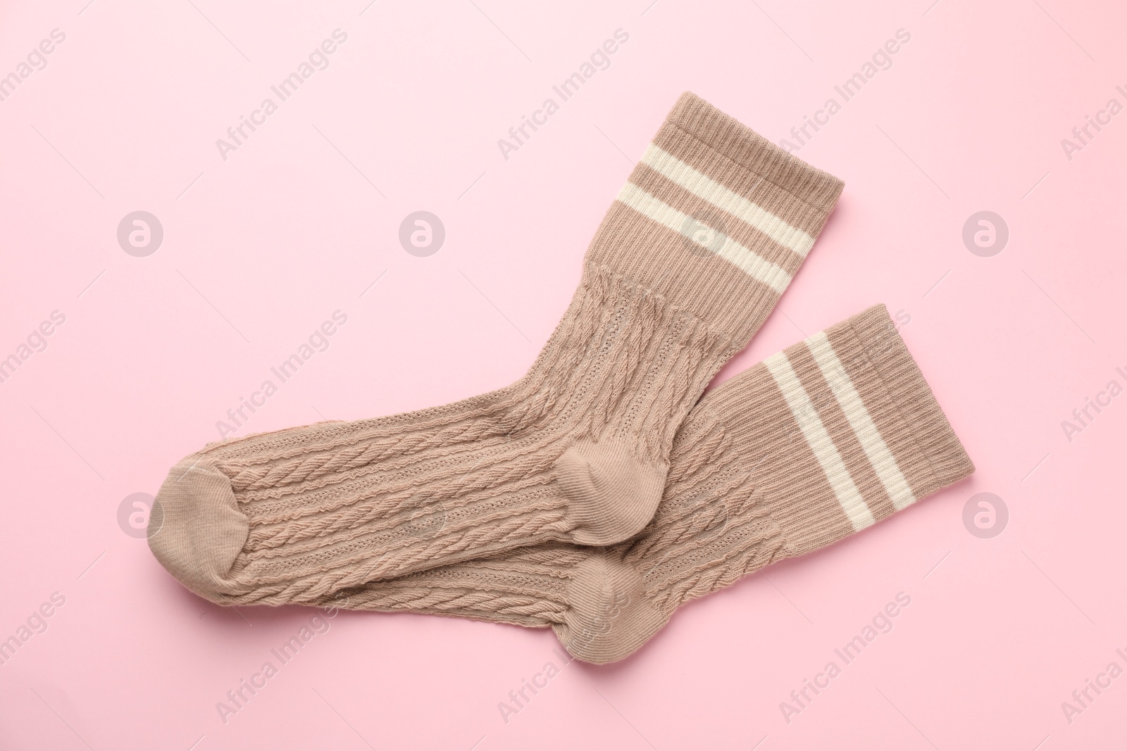 Photo of Pair of soft comfortable socks on light pink background, top view