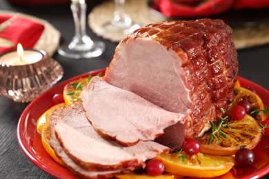 Tasty baked ham served on black wooden table, closeup